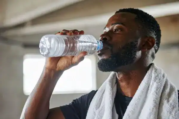 Hydration: The Secret Ingredient for a Toned Stomach and Enhanced Fitness 1 Image of man drinking water to improve hydration Hastings after work out.